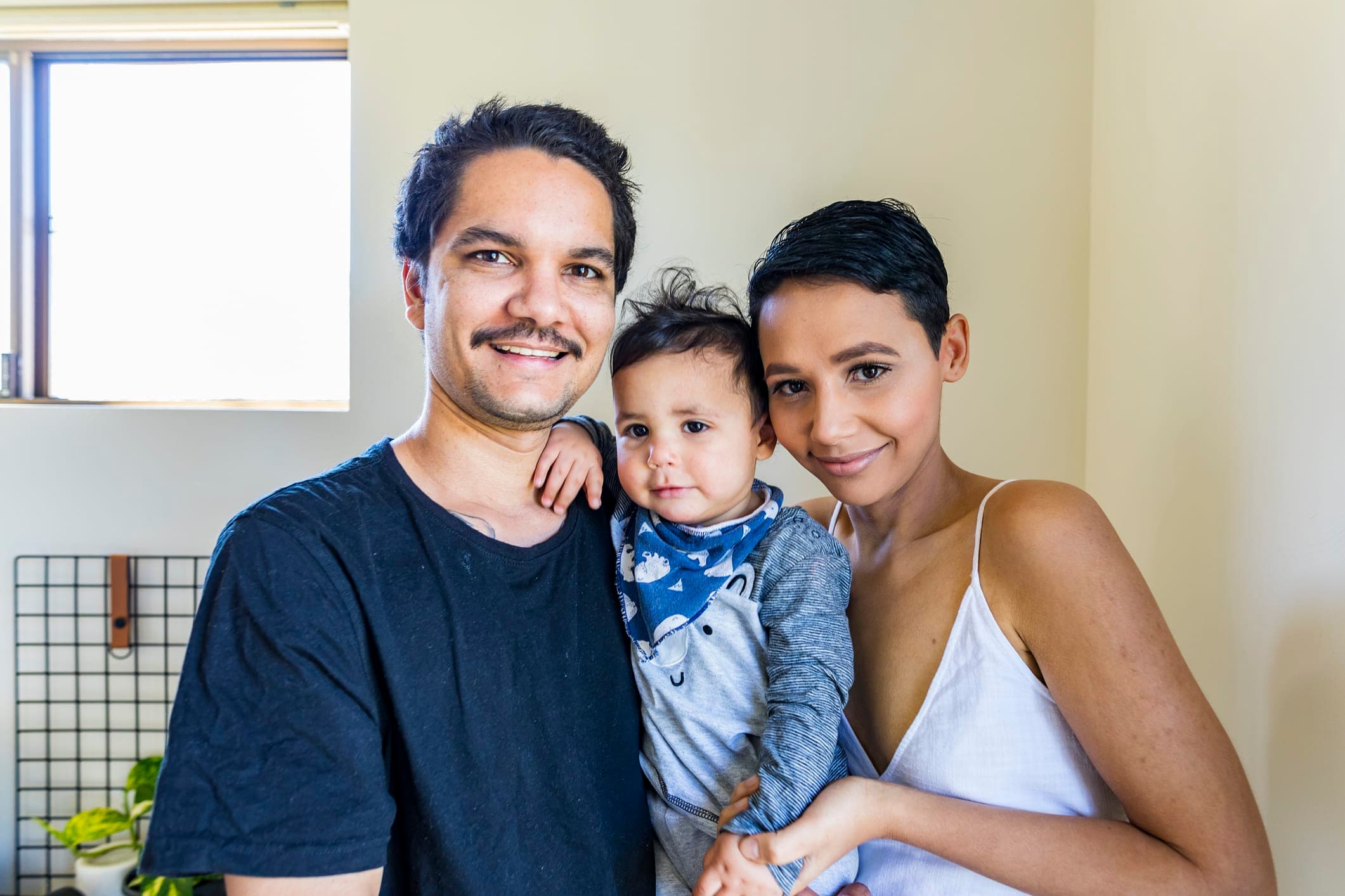 A family - a couple holding their young child facing the camera